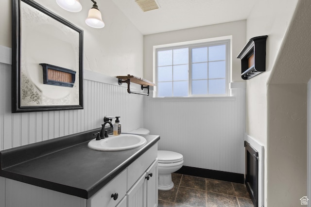 2599 S Foxridge Rd, Garden City, UT 84028 - bathroom featuring vanity, visible vents, toilet, and wainscoting