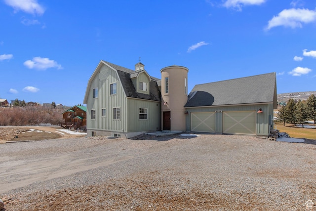 2599 S Foxridge Rd, Garden City, UT 84028 - view of front of house featuring an attached garage, a gambrel roof, roof with shingles, driveway, and an outbuilding