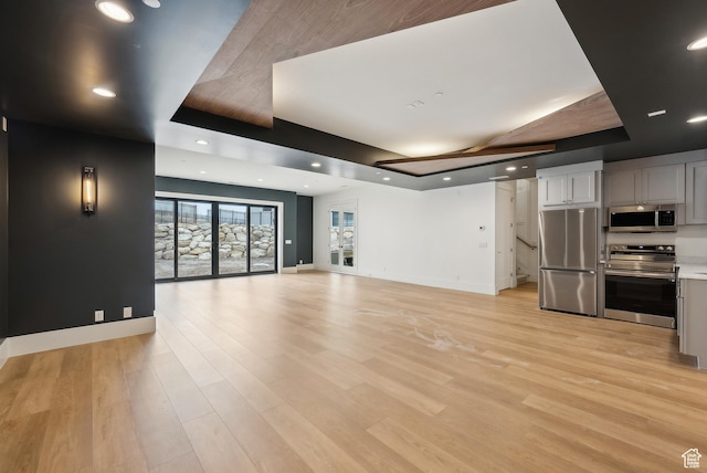13042 N Prospector Way, Alpine, UT 84004 - unfurnished living room with a raised ceiling, baseboards, light wood-style floors, and recessed lighting