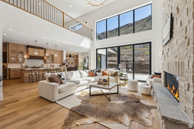 13042 N Prospector Way, Alpine, UT 84004 - living room with a towering ceiling, light wood finished floors, a stone fireplace, a mountain view, and recessed lighting