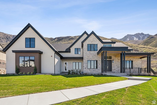 modern inspired farmhouse with a mountain view, a front lawn, stucco siding, and covered porch