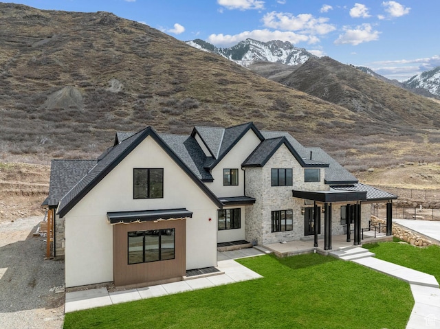 view of front of property featuring stone siding, a mountain view, and a front lawn