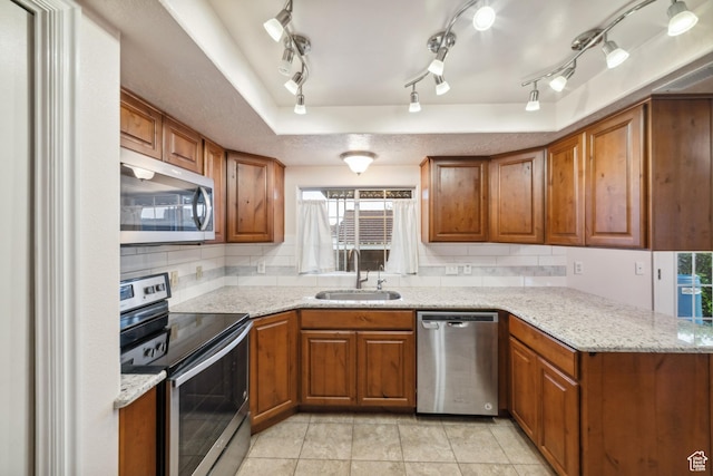 kitchen with a sink, decorative backsplash, brown cabinets, and stainless steel appliances