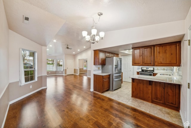 kitchen featuring a sink, vaulted ceiling, brown cabinets, and appliances with stainless steel finishes