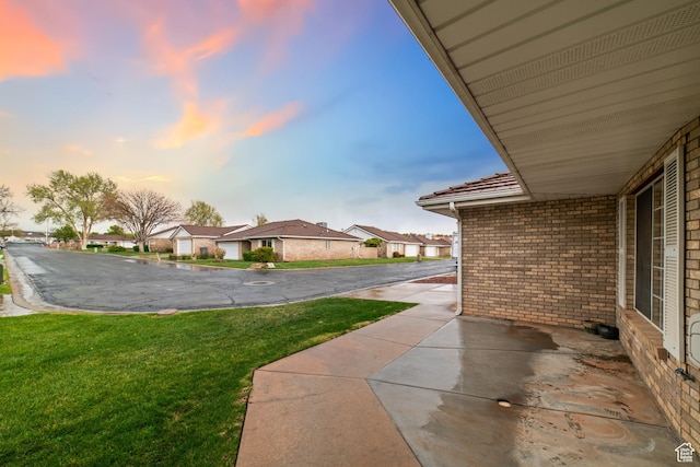 yard at dusk featuring a residential view