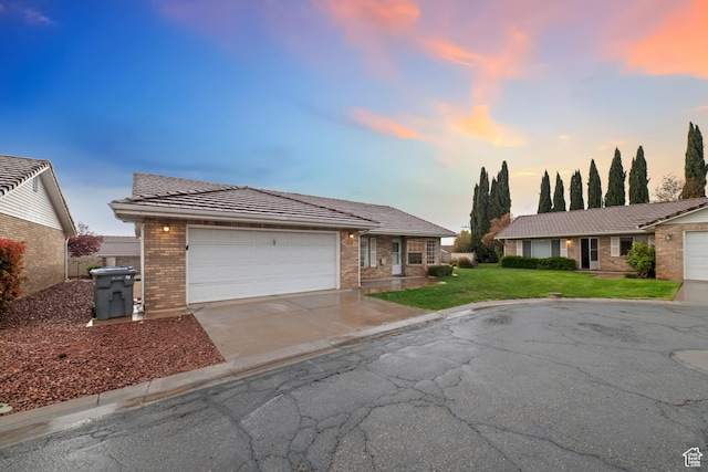single story home with a lawn, an attached garage, concrete driveway, and brick siding