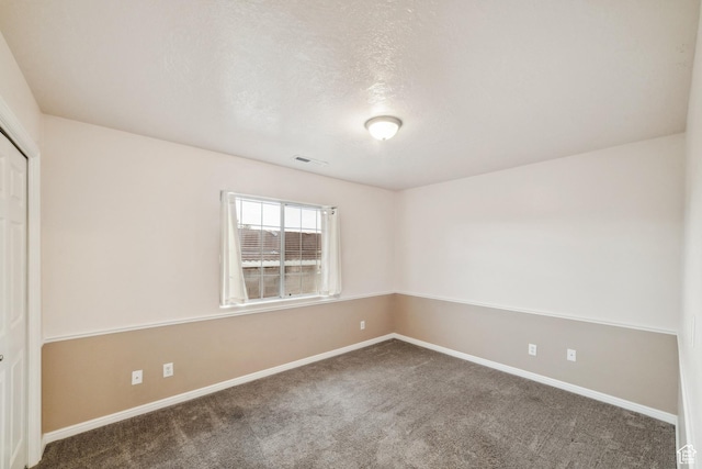 spare room with baseboards, a textured ceiling, visible vents, and carpet