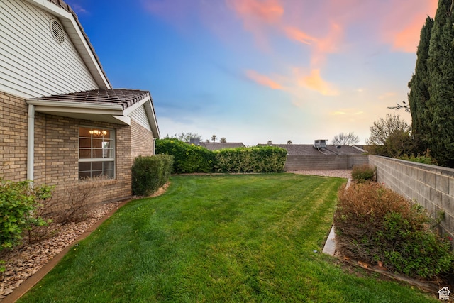yard at dusk featuring a fenced backyard