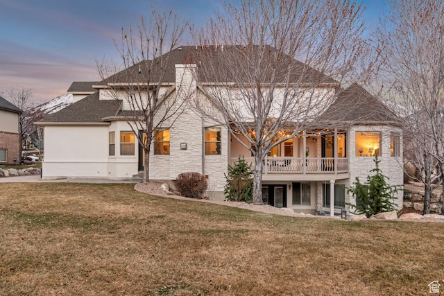 12483 N Timberline Dr, Highland, UT 84003 - rear view of property with stone siding, a shingled roof, stucco siding, and a lawn