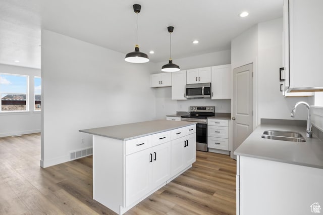kitchen with light wood finished floors, a sink, visible vents, and appliances with stainless steel finishes