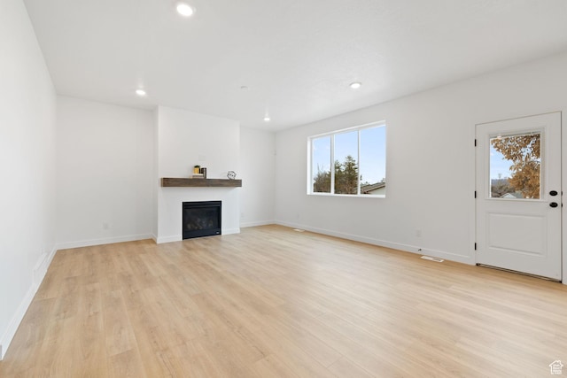 695 N Plainsman Dr Unit 110, Spanish Fork, UT 84660 - unfurnished living room featuring baseboards, recessed lighting, a glass covered fireplace, and light wood-style floors