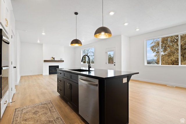 695 N Plainsman Dr Unit 110, Spanish Fork, UT 84660 - kitchen with a glass covered fireplace, light wood-style floors, dark cabinetry, appliances with stainless steel finishes, and a sink