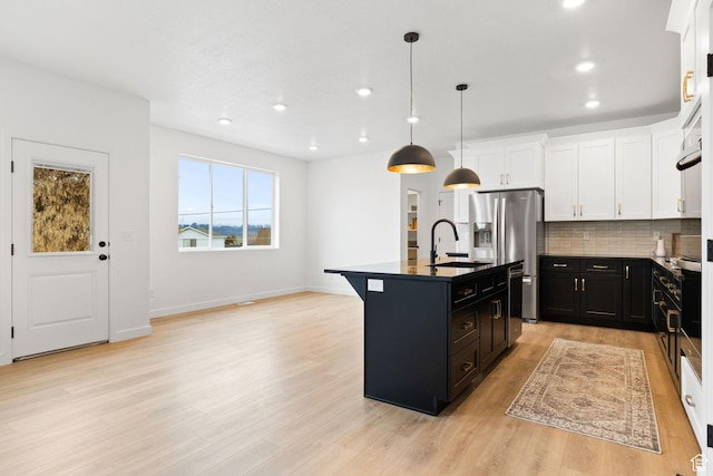 695 N Plainsman Dr Unit 110, Spanish Fork, UT 84660 - kitchen with light wood-type flooring, a sink, dark countertops, dark cabinetry, and backsplash