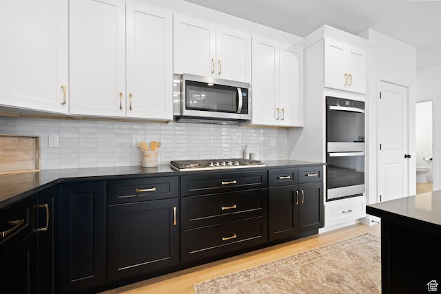 695 N Plainsman Dr Unit 110, Spanish Fork, UT 84660 - kitchen with white cabinets, light wood-type flooring, dark cabinetry, and appliances with stainless steel finishes