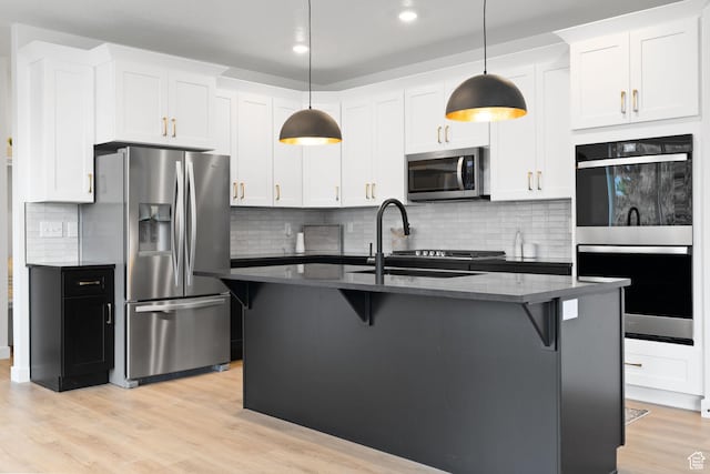 695 N Plainsman Dr Unit 110, Spanish Fork, UT 84660 - kitchen featuring stainless steel appliances, light wood-type flooring, a kitchen breakfast bar, and backsplash