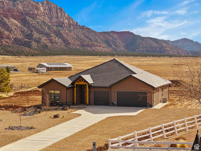 view of front of house with a tile roof, concrete driveway, fence, a garage, and a mountain view