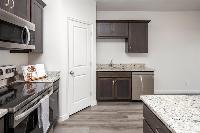 250 W 1200 S Unit 118, Tremonton, UT 84337 - kitchen with a sink, light wood-style flooring, light stone countertops, dark brown cabinets, and appliances with stainless steel finishes