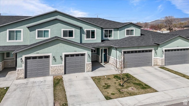 250 W 1200 S Unit 118, Tremonton, UT 84337 - view of front of property featuring stucco siding, stone siding, driveway, a garage, and a shingled roof