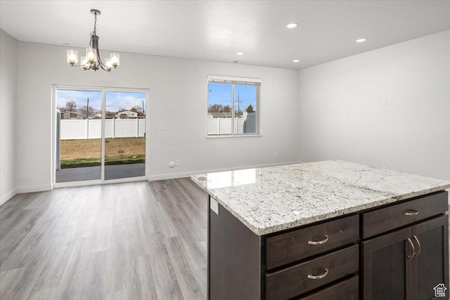 250 W 1200 S Unit 118, Tremonton, UT 84337 - kitchen featuring light wood finished floors, baseboards, light stone countertops, dark brown cabinets, and an inviting chandelier