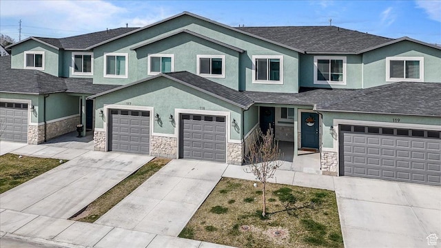 view of front of home with stone siding, a garage, driveway, and stucco siding