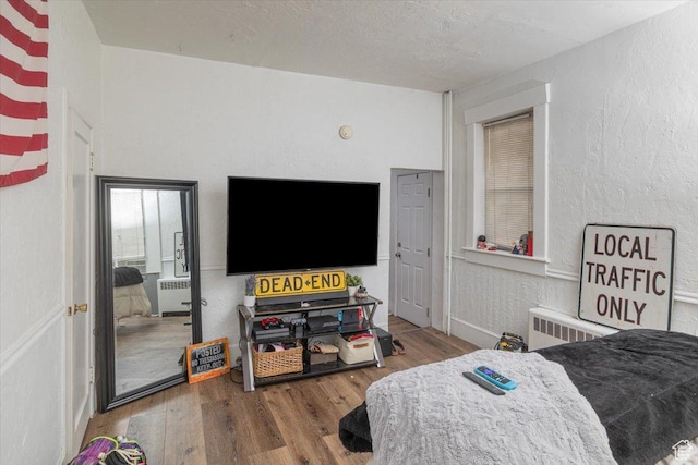 263 W Center St, Logan, UT 84321 - bedroom with wood finished floors, radiator heating unit, a textured wall, and a textured ceiling