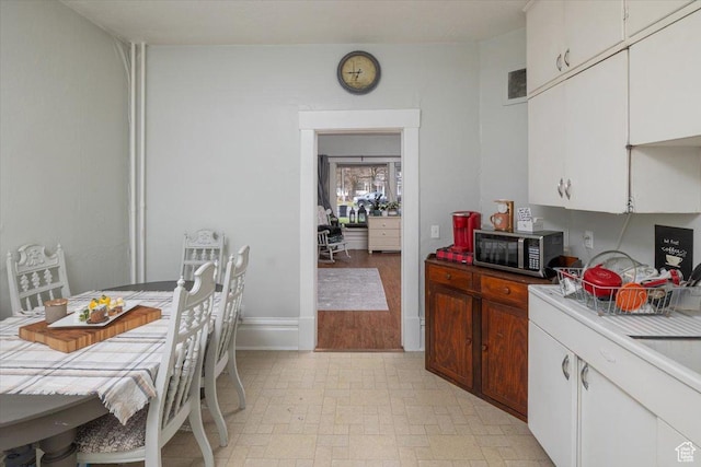 263 W Center St, Logan, UT 84321 - kitchen with light countertops, stainless steel microwave, baseboards, visible vents, and white cabinets