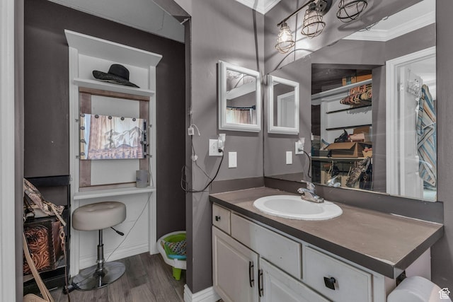 bathroom featuring baseboards, wood finished floors, vanity, and ornamental molding