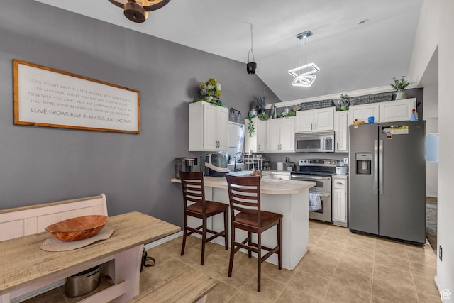 kitchen featuring a kitchen bar, a peninsula, vaulted ceiling, stainless steel appliances, and white cabinets