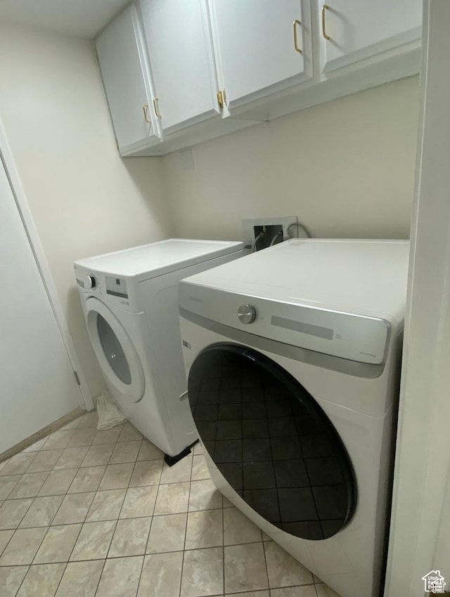 laundry room with light tile patterned floors, cabinet space, and washer and clothes dryer