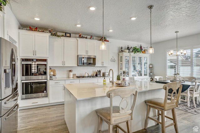 1002 E 2680 S, Heber City, UT 84032 - kitchen featuring white cabinetry, stainless steel appliances, an inviting chandelier, and light wood finished floors