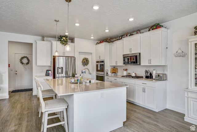 1002 E 2680 S, Heber City, UT 84032 - kitchen with decorative backsplash, light wood-style flooring, stainless steel appliances, an island with sink, and a sink