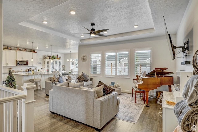 1002 E 2680 S, Heber City, UT 84032 - living room featuring a textured ceiling, a ceiling fan, light wood-style floors, and a raised ceiling