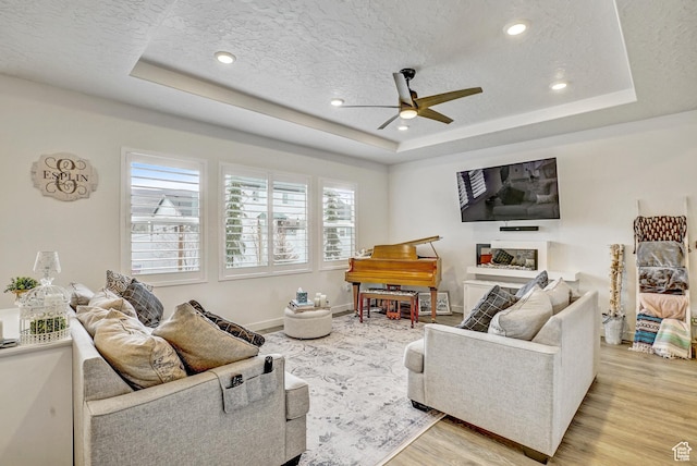1002 E 2680 S, Heber City, UT 84032 - living room featuring a textured ceiling, light wood-type flooring, a ceiling fan, and a raised ceiling