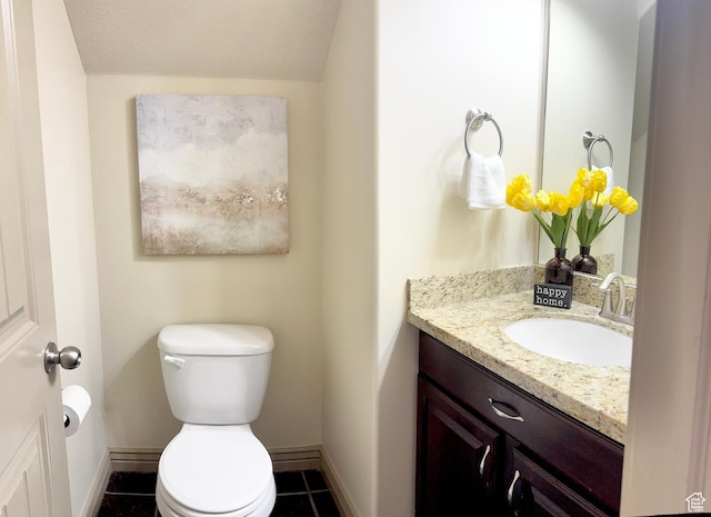 half bathroom featuring toilet, vanity, baseboards, and tile patterned flooring