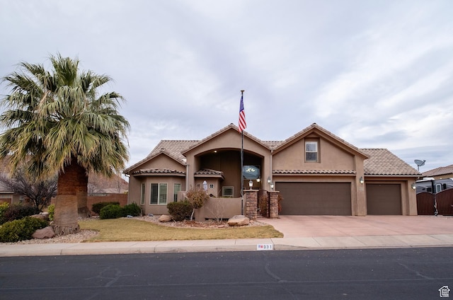 view of front facade with fence, an attached garage, concrete driveway, a tile roof, and stucco siding