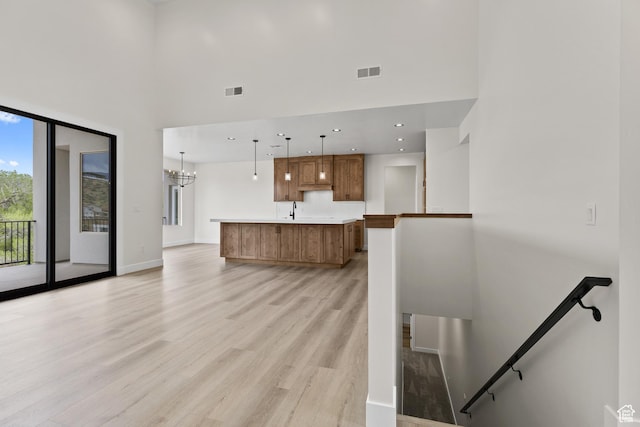 interior space with a high ceiling, visible vents, light wood-type flooring, and a sink