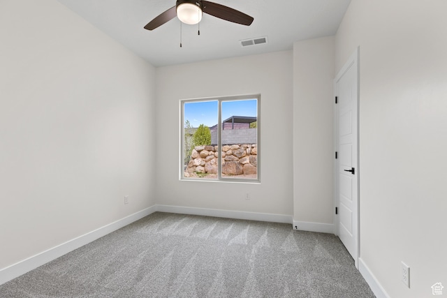 carpeted spare room featuring baseboards, ceiling fan, and visible vents