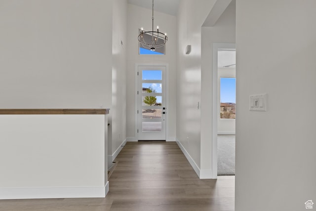 entrance foyer featuring baseboards, a notable chandelier, a high ceiling, and wood finished floors