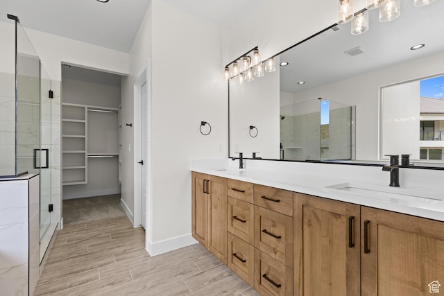full bathroom featuring double vanity, a sink, a stall shower, and wood finish floors