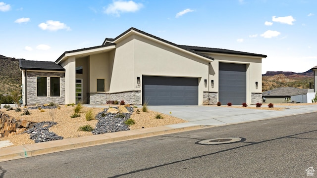 view of front of home featuring stone siding, an attached garage, concrete driveway, and stucco siding
