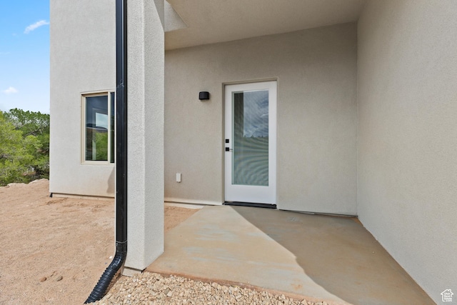 entrance to property with stucco siding and a patio area
