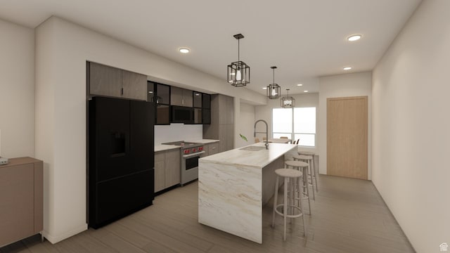 4350 S 900 E, Millcreek, UT 84124 - kitchen featuring light countertops, a kitchen bar, a sink, high end stove, and black refrigerator with ice dispenser