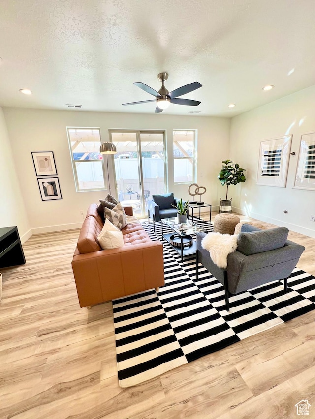 living room with ceiling fan, light wood-type flooring, plenty of natural light, and baseboards