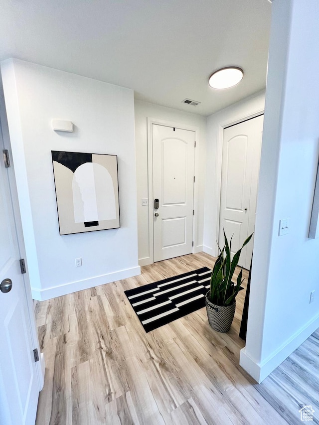 entryway with wood finished floors, baseboards, and visible vents
