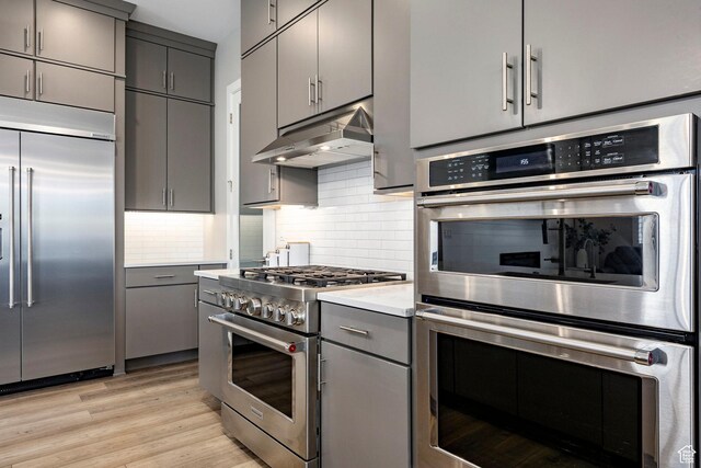 14902 S Fawley Ln, Herriman, UT 84096 - kitchen featuring gray cabinets, under cabinet range hood, tasteful backsplash, and premium appliances