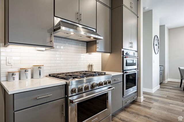 14902 S Fawley Ln, Herriman, UT 84096 - kitchen with gray cabinetry, appliances with stainless steel finishes, baseboards, and under cabinet range hood