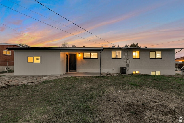 back of house featuring central air condition unit, fence, a lawn, brick siding, and a patio area