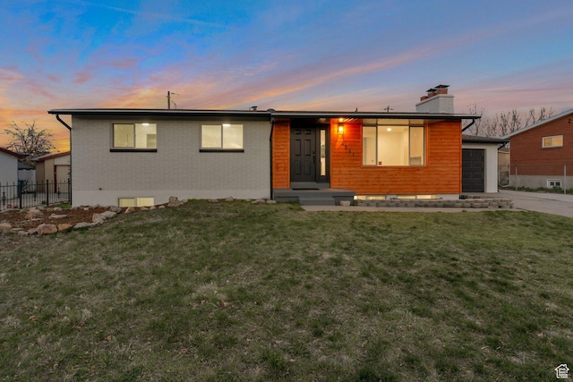 view of front of house featuring a chimney, fence, brick siding, and a front yard