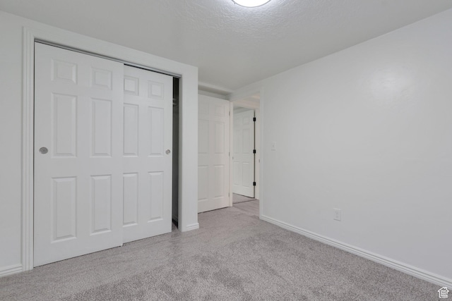 unfurnished bedroom with a closet, carpet, baseboards, and a textured ceiling
