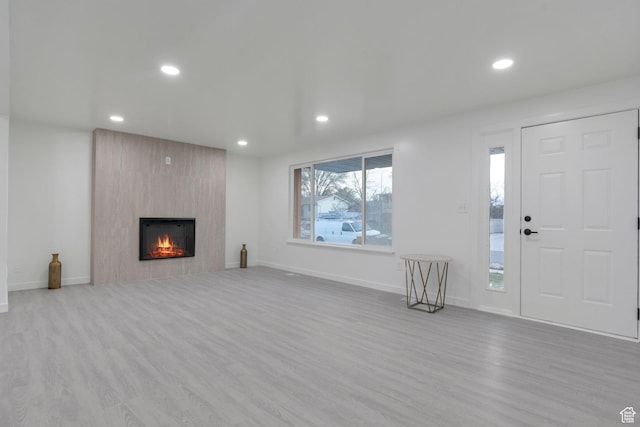 unfurnished living room with baseboards, recessed lighting, wood finished floors, and a large fireplace